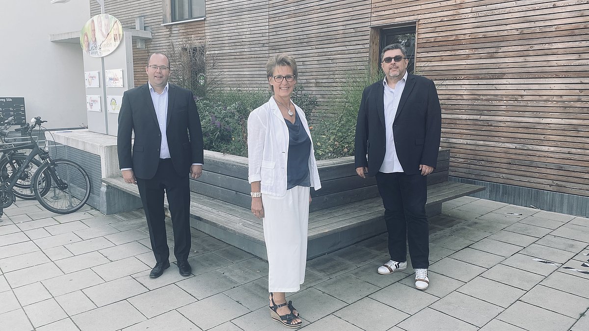 Drei Menschen stehen vor einem Haus Drei Menschen stehen vor einem Haus