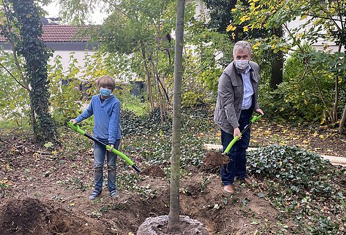 Zehnjährger Junge und Bürgmeister Kurt Krömer planzen einen Baum
